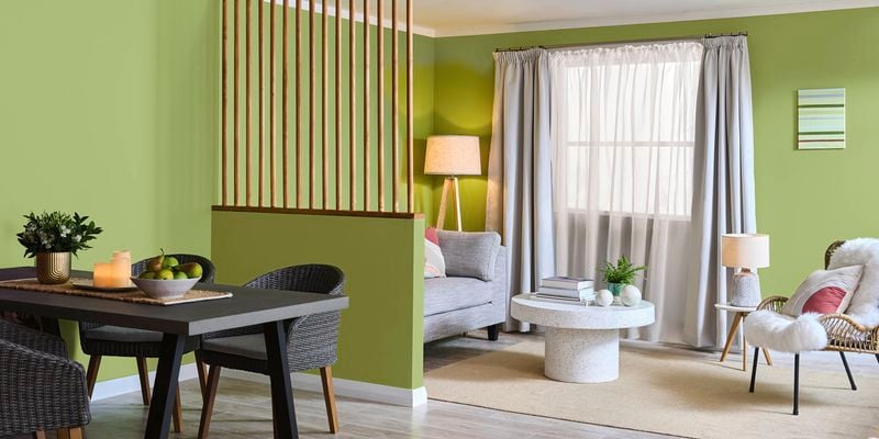 A dining table divided by a lime green wall with a loungeroom setting showing living flexible spaces