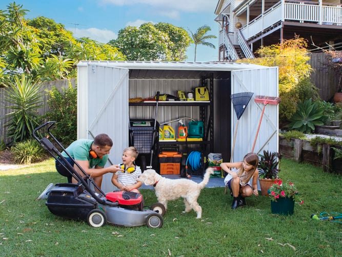 A family with a dog outside in front of a garden shed.