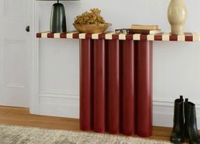 A completed hallway console table made from red cylindrical legs with a striped tabletop, styled with decor in a home interior.