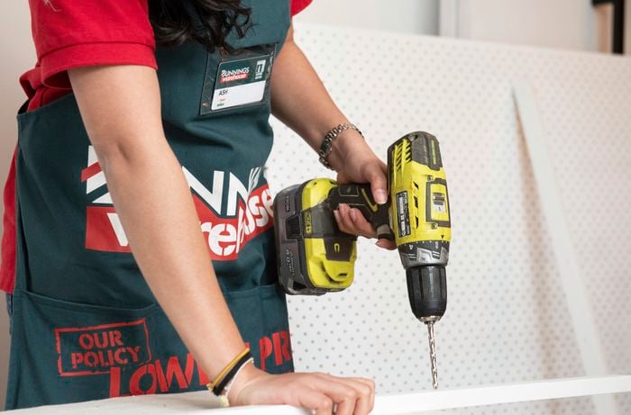 Person drilling into thin piece of white timber.