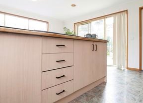 Kitchen bench with woodgrain cupboards and black handles