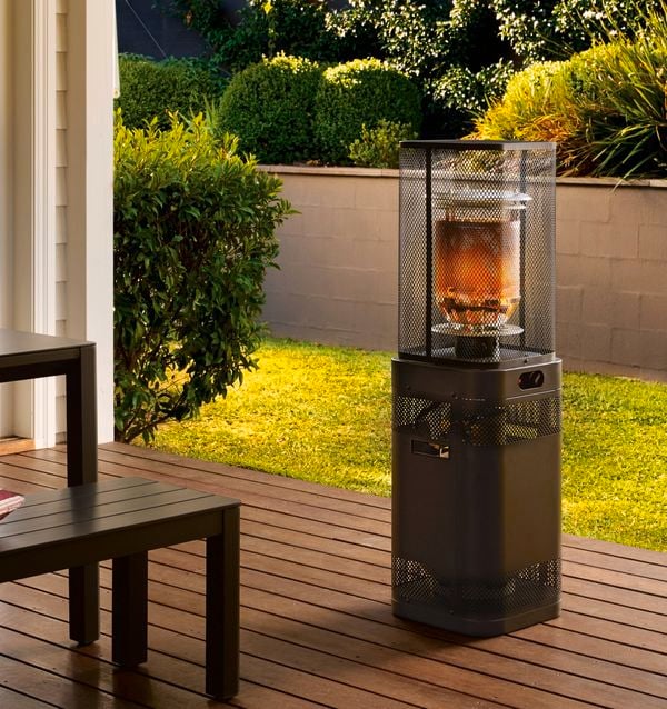 A patio heater on decking outside with lawn around it.