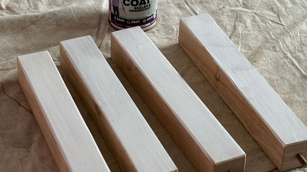 Four timber table legs and a tin of primer on a drop sheet.
