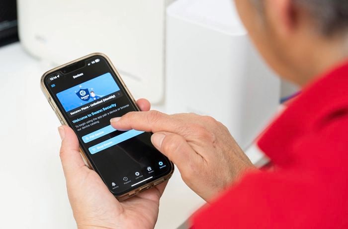 A person is using the Swann Security mobile app on their smartphone to connect the hub, offering flexibility and peace of mind from anywhere.