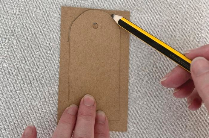 Pencil traces outline of gift card on cardboard