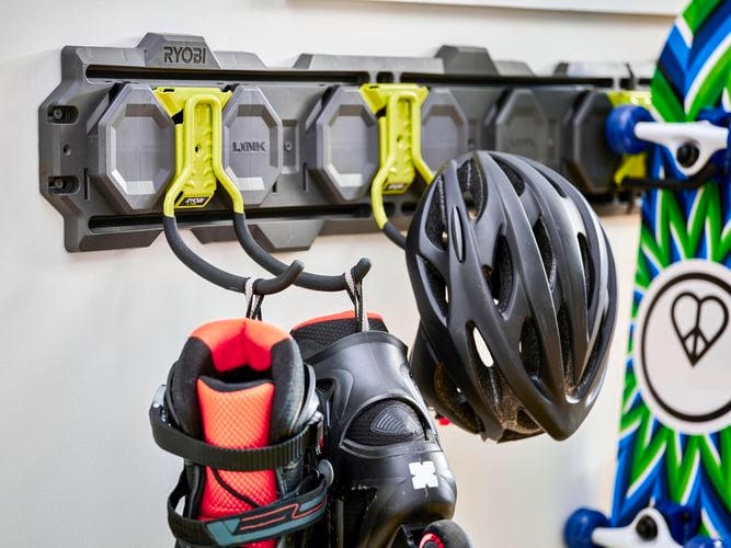 Roller skates, helmet and skateboard hanging off hooks.