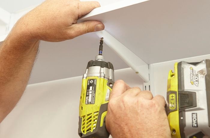 Connecting the shelf brackets to the upright wall bracket with a Ryobi drill