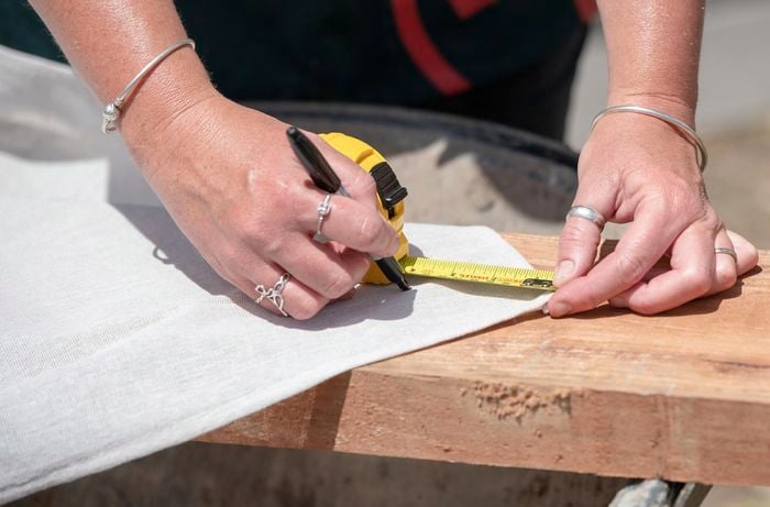 Person measuring a sheet of canvas with a measuring tape