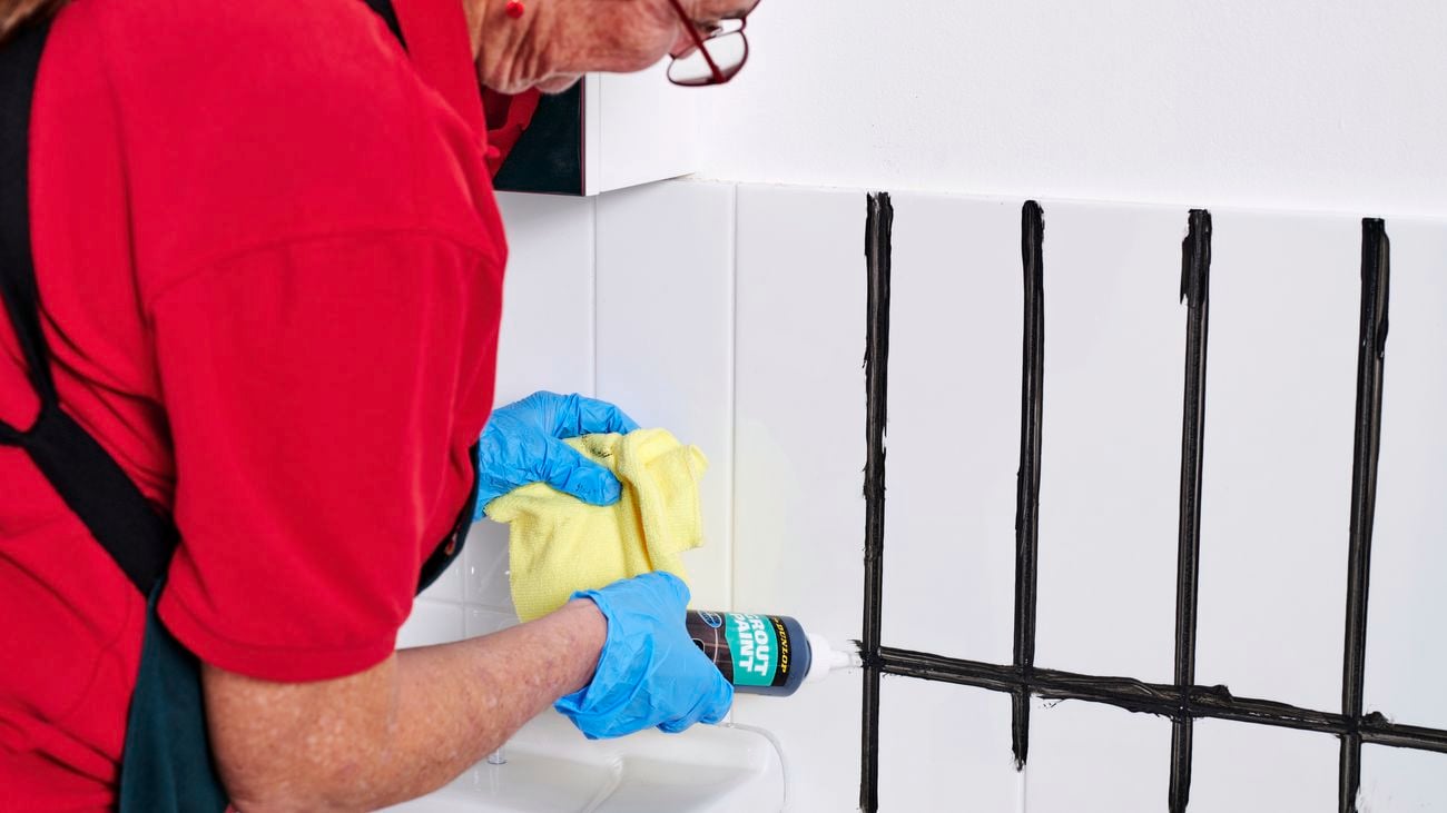 Person in Bunnings uniform uses applies new grout to bathroom tiles