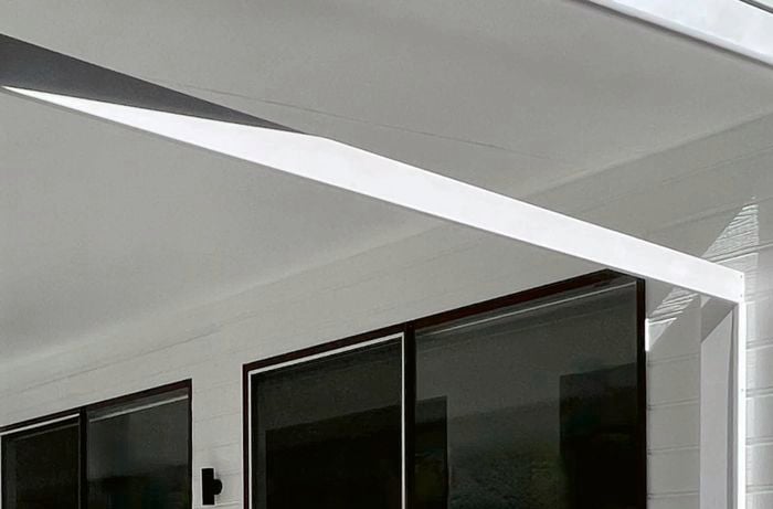 Two, white, pine rails are placed between the side of the house and up to the roof of the outdoor area.