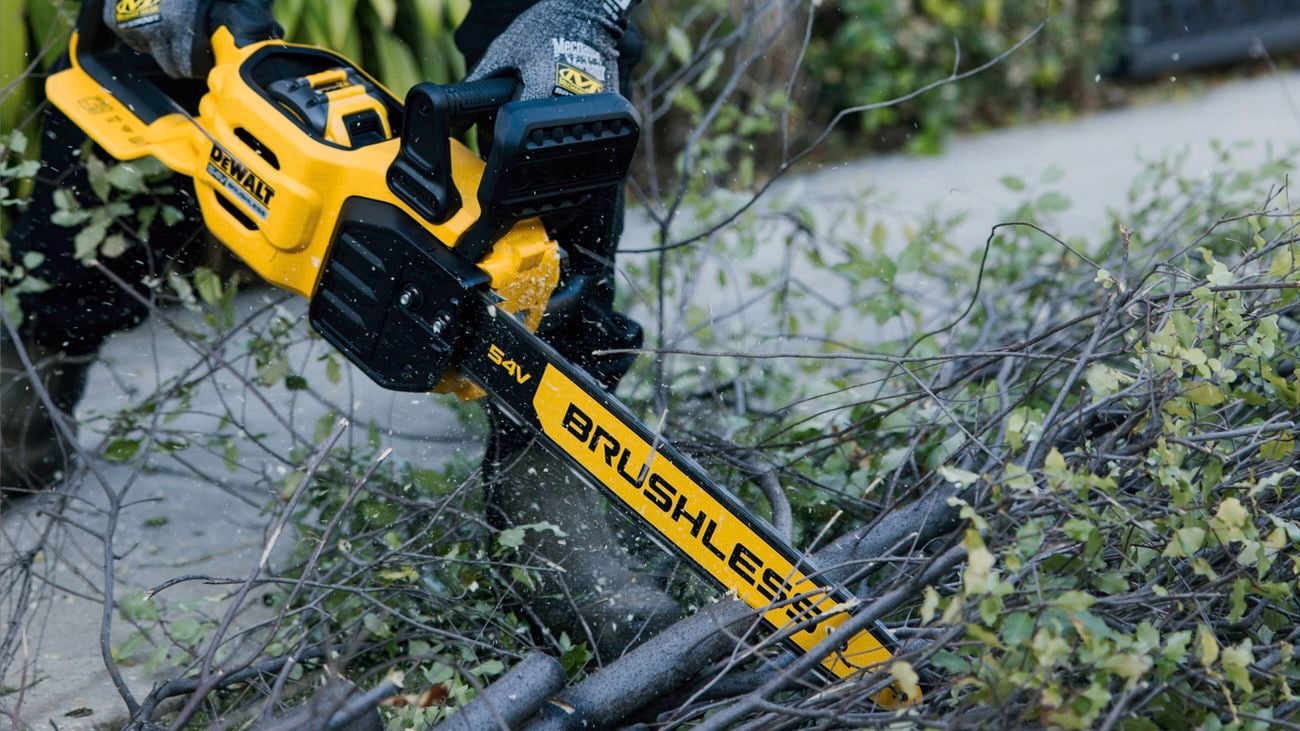 A close up image of a DeWALT 54V 45cm Cordless Chainsaw cutting through a branch
