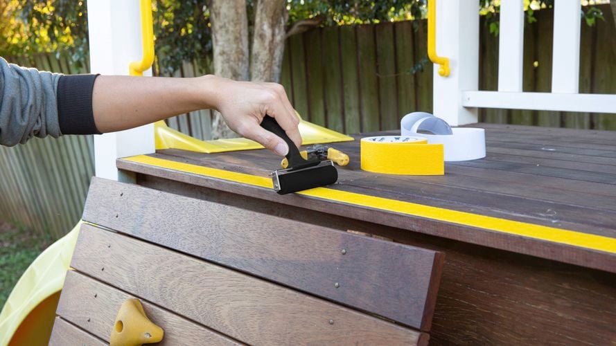 Applying adhesive tread on play equipment.