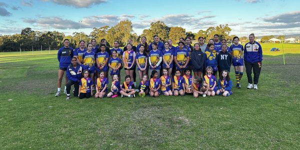 Junior and youth football players pose together on a sports field during a community training or development session.