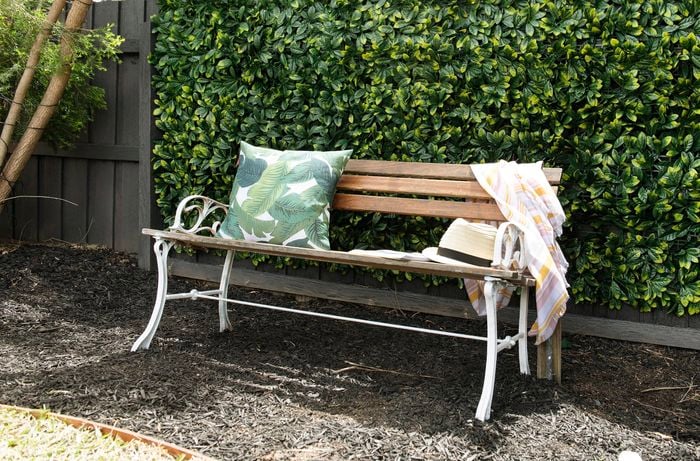 Bench seat in front of artificial hedging.