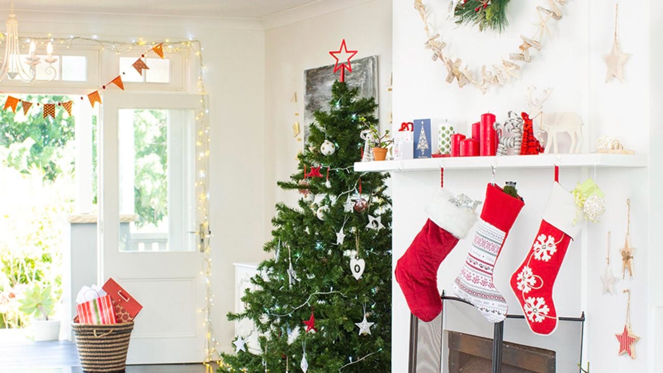 Living room decorated with a Christmas tree, bunting, fairy lights and stockings hanging over a fireplace