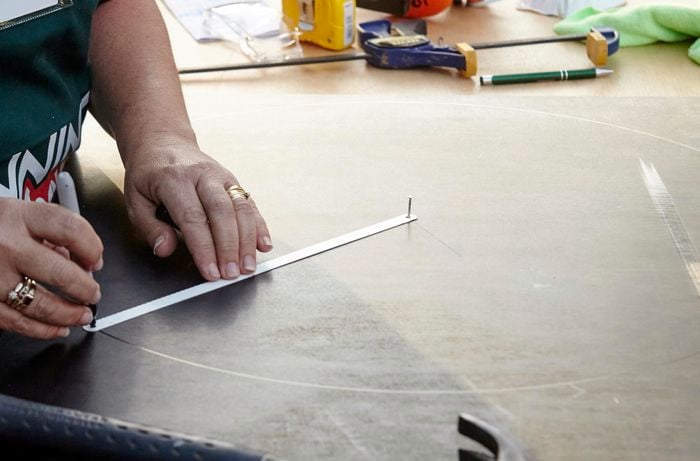 A person marking a circle onto a piece of formply