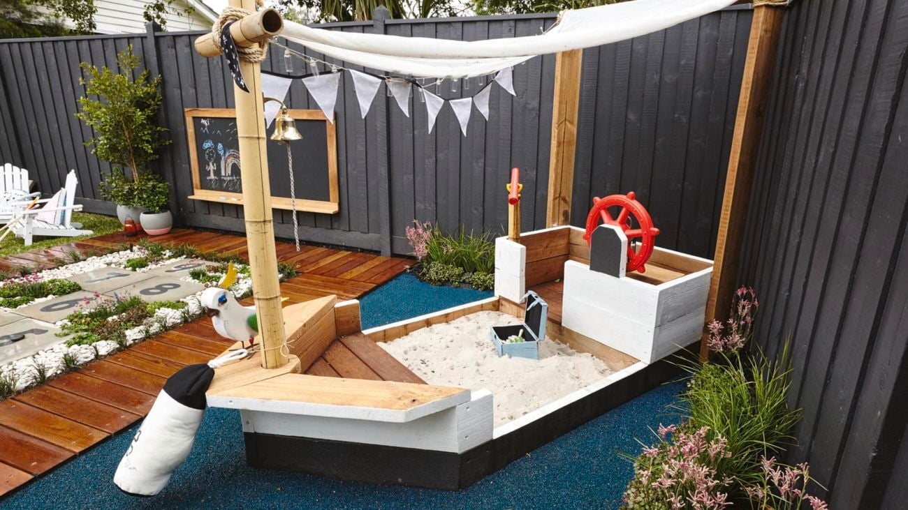 Backyard area with pirate ship play area, hopscotch and chalkboard on fence.