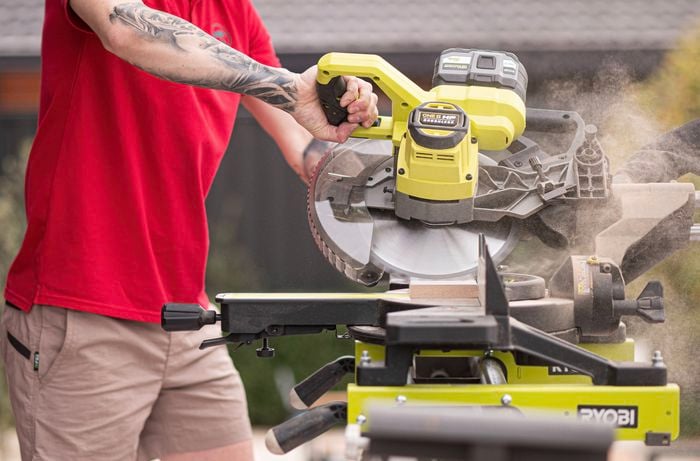 A Bunnings Team Member is cutting a skirting board using a Ryobi mitre saw. 