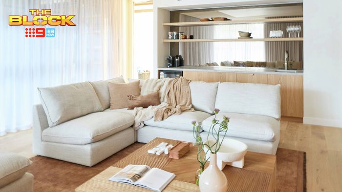 Contemporary living room featuring a large cream sectional sofa, timber coffee table and built-in timber cabinetry with open shelving.
