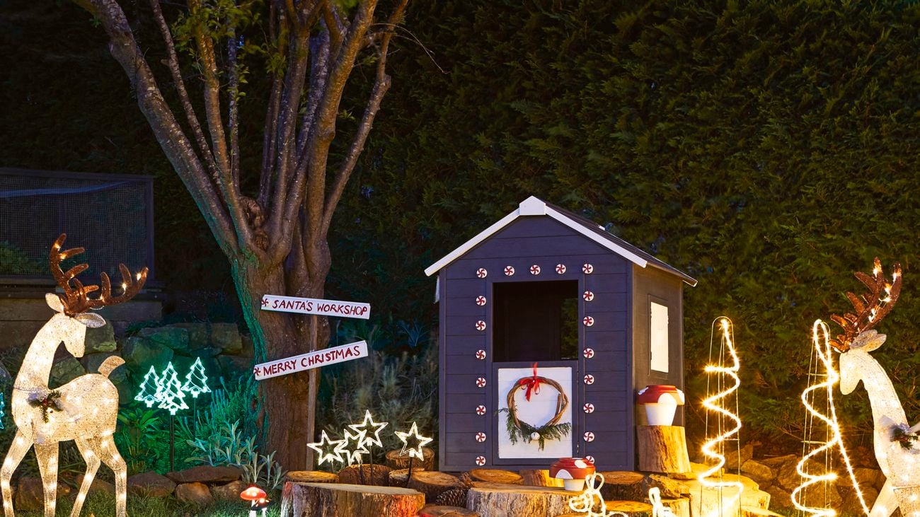 Illuminated reindeer, kangaroos and stars next to a decorated cubby house at night