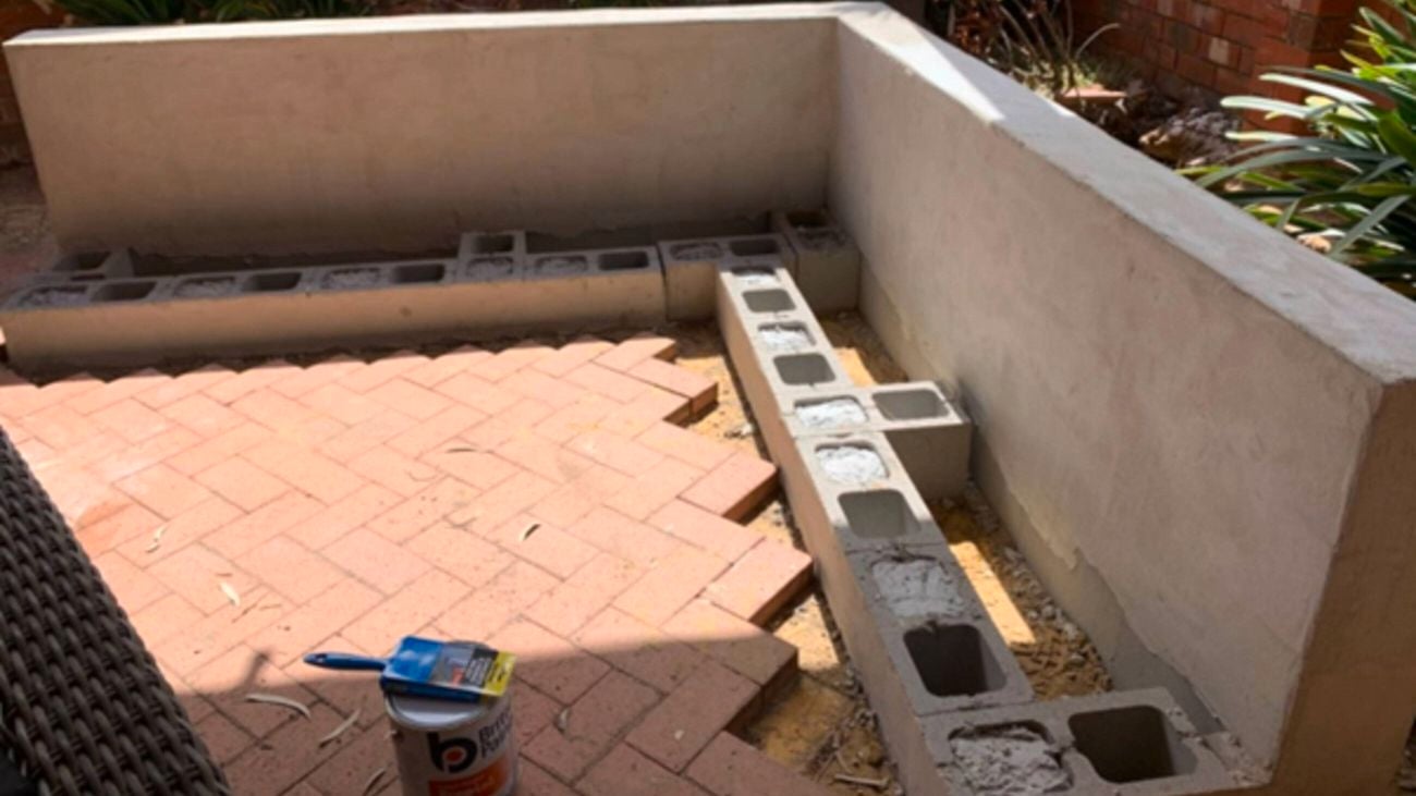 Birds eye view of grey large Brickwork being ensembled into a L shape, this is going to create a floating outdoor l shape bench seat.