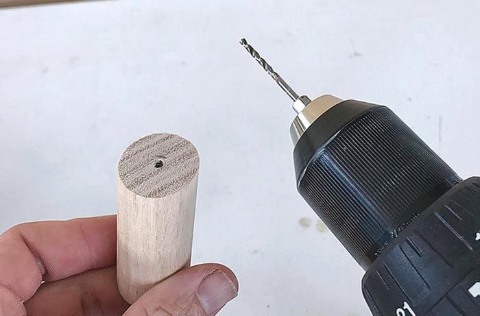 Holes being drilled into the base of a dowel peg for securing to a coat rack