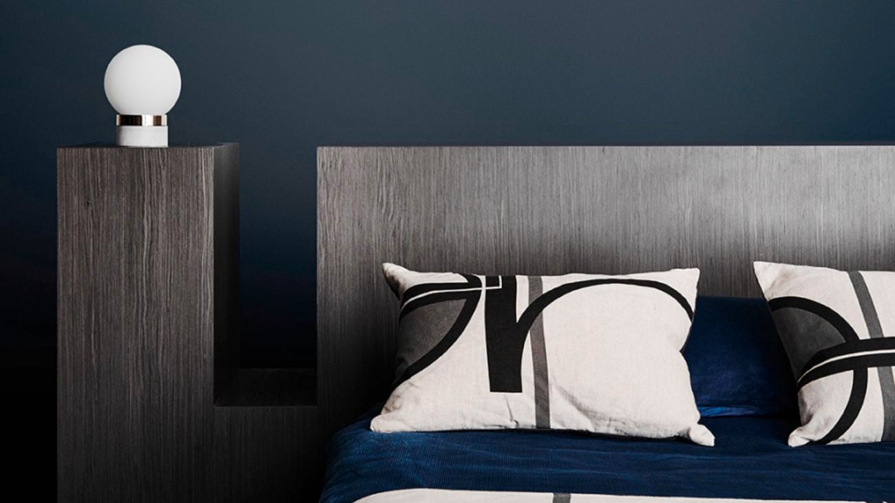 Bedroom with dark blue walls and a timber bedhead.