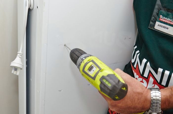Using the drill to pre-drill the six holes into the back of the ironing centre.