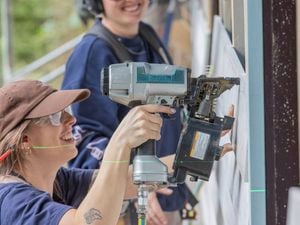 A young woman in construction using a Makita nail gun on a building site