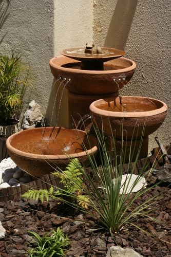 Descending diagonal pots on a wall with water trickling from one to another