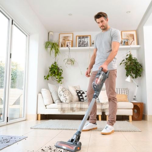man using stick vac to clean dirt off tiled floor