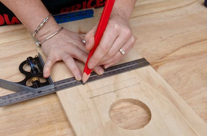 A plank of wood being marked with a ruler and tape measure