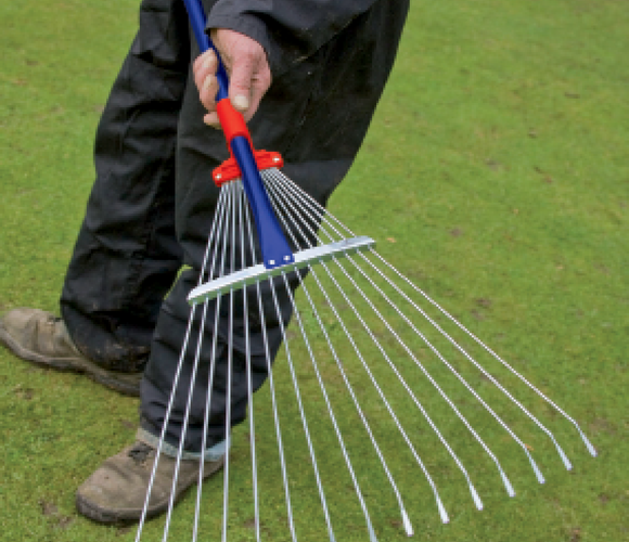 Person holding a metal leaf rake