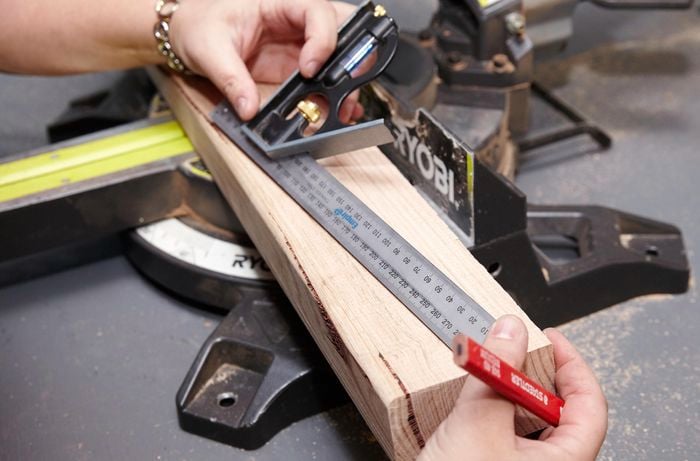 Person using ruler to measure a cut to be made on piece of timber