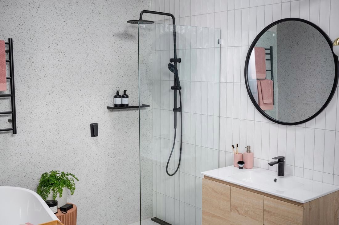 Bathroom with marble wall and white tiled walls with black colour fittings. 