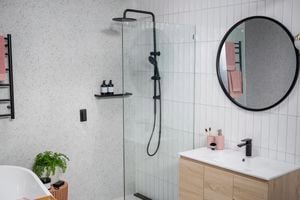 Bathroom with marble wall and white tiled walls with black colour fittings. 