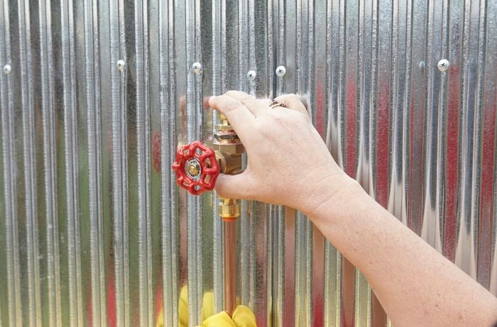 Person holding shower tap against wall, determining where it will be placed.