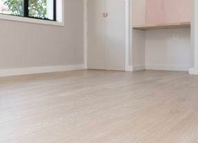 a completed room with light wood laminate flooring, a window, a built-in shelf, and a closed door.