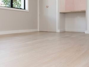 a completed room with light wood laminate flooring, a window, a built-in shelf, and a closed door.
