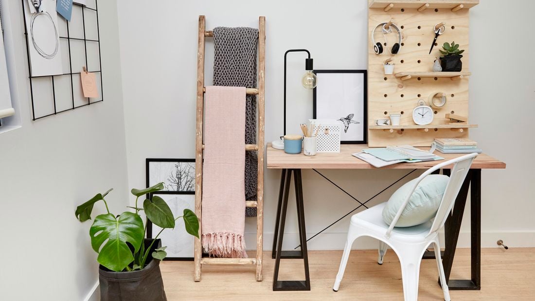 Home office with desk, chair, plant, timber ladder, and pegboard shelf.