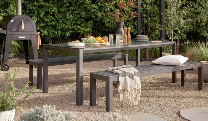 Food on outdoor table & benches with a outdoor pizza oven in backyard