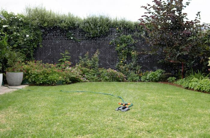 A lawn with a sprinkler watering the grass.