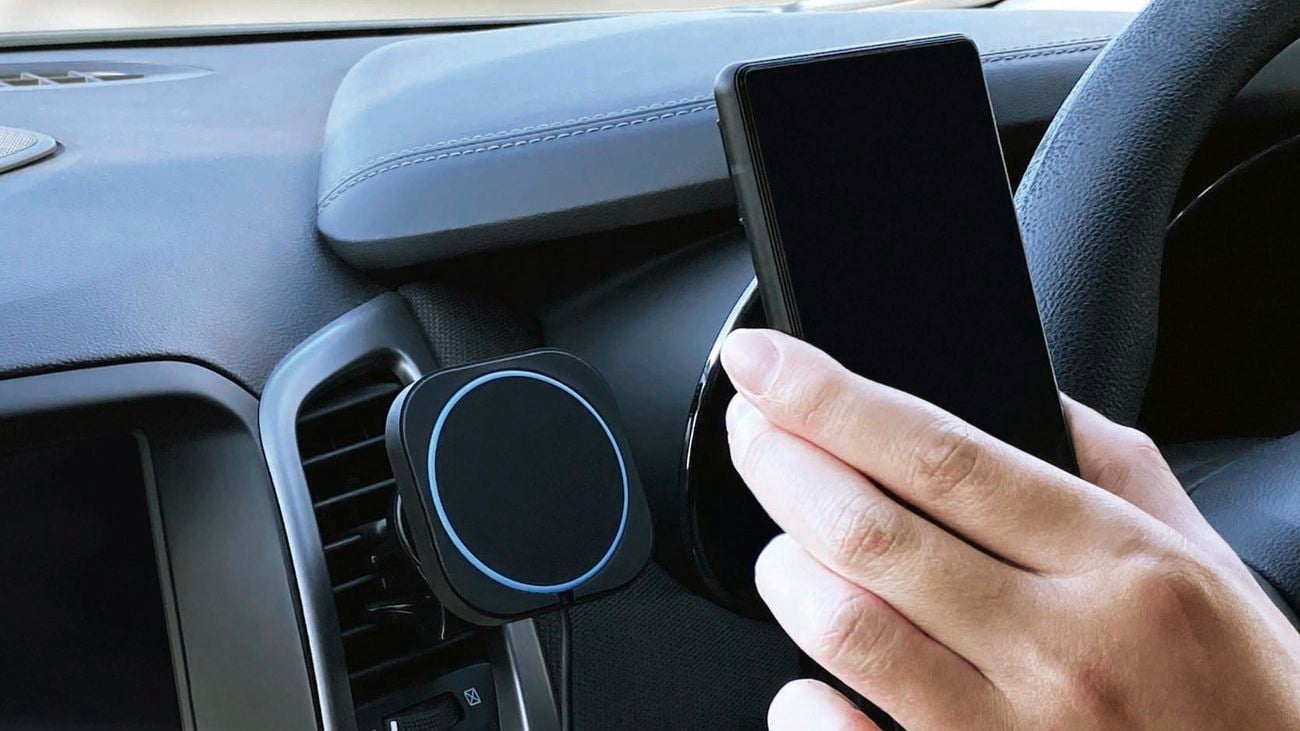Hand holding phone in car with car charger attached to dashboard 
