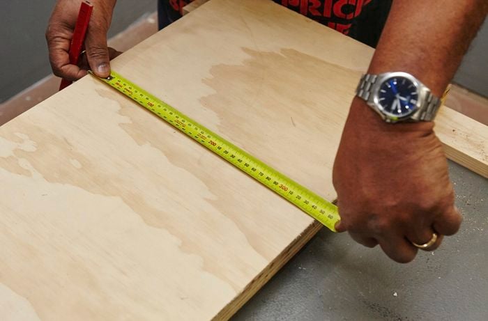 A panel of wood being measured for a bar stool seat to be cut from it