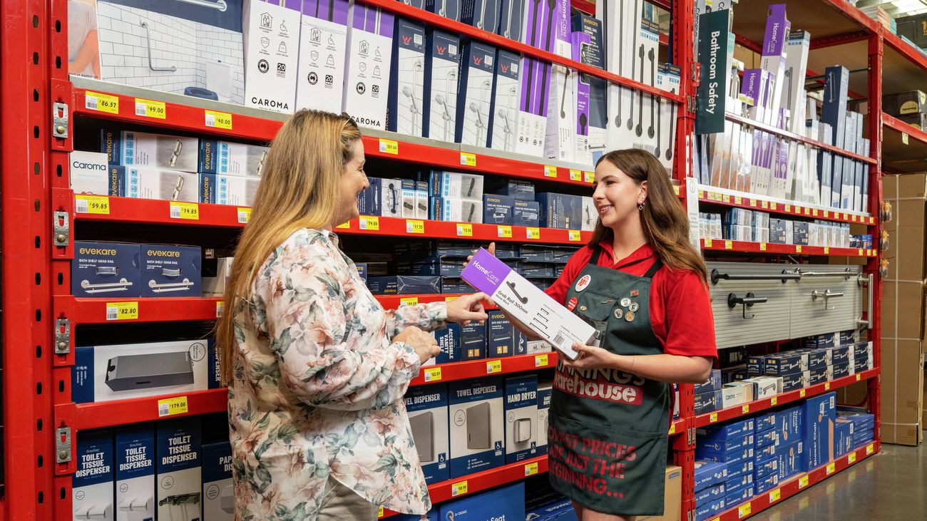 A woman with long blonde hair talks to a Bunnings Warehouse red shirt about the Assisted Living range]