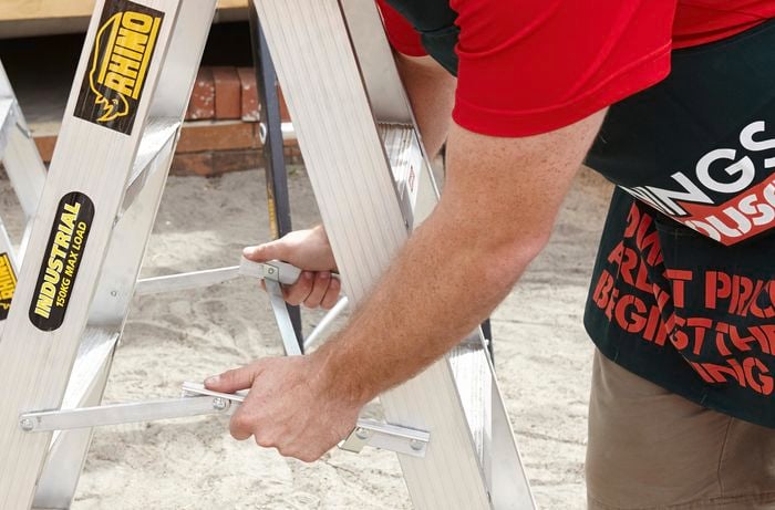A person locking the horizontal arms on a ladder