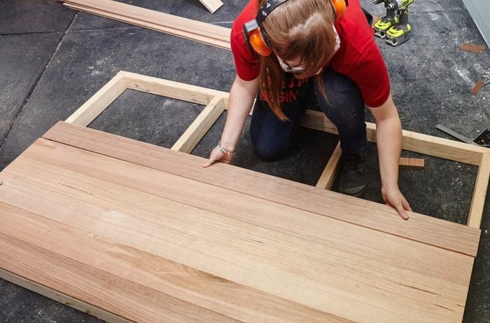 Person laying timber pieces down on top of timber bedhead frame.