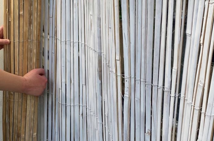 A close up of an upcycled bamboo screen spray painted white being rolled out.