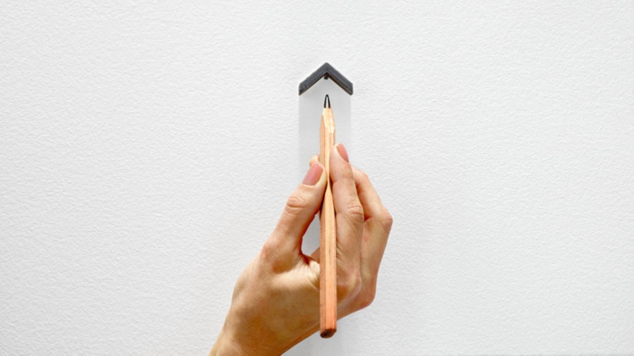 Hand marks spot on a wall with a pencil using a spot marker.