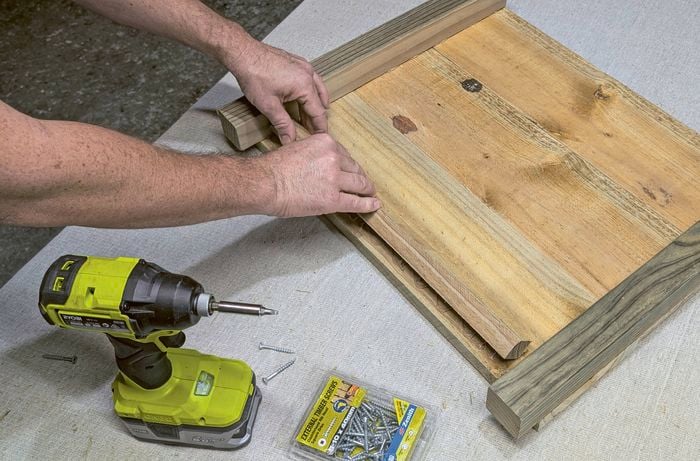 Hands attaching a base support to a timber panel with adhesive